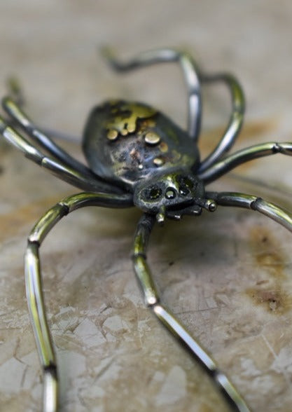 Large spider brooch by Peggy Skemp with fibula pin. Spider has white yellow and rose gold adornments on its back, hand engraved texture and 4 black diamond eyes, hand engraved legs.
