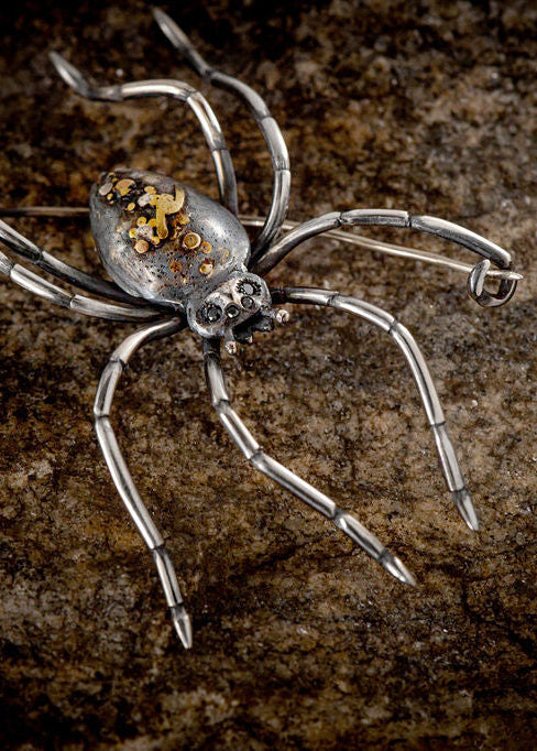 Large spider brooch by Peggy Skemp with fibula pin. Spider has white yellow and rose gold adornments on its back, hand engraved texture and 4 black diamond eyes, hand engraved legs.