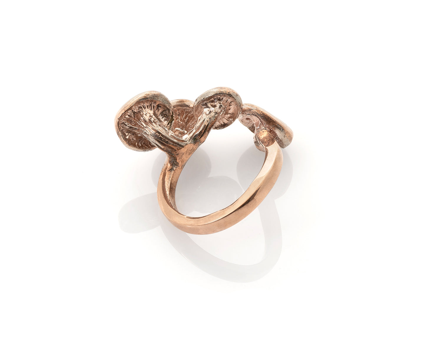 golden oyster mushroom ring. home grown golden oyster mushrooms were grown in logs, cast in silver, molded and then sculpted with a smooth 3mm ring shank. The ring is adjustable with 3 golden oyster mushrooms on top. They come either gold plated, with the gold fading to silver on the shank, or antique finished (oxidized black then repolished,) or in carnation pink silver. The ring is adjustable. This photo, by photographer Rachel Hanel, is a product shot with a white background,is of the side view.