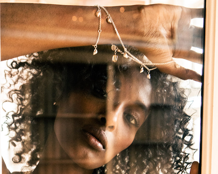 Multi shell necklace, product photo on pink and white marble, showing the texture of each little shell.