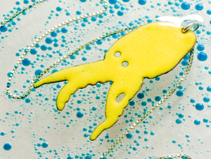 glass enamelled squid silhouette, profile of squid with cutout eyes, bright lime green vitreous glass enamel, fired to a high gloss finish, by peggy skemp 2008, sold at Wolfbait and B Girls, Chicago, IL. Photo with blue bubbles by AJ Kane.