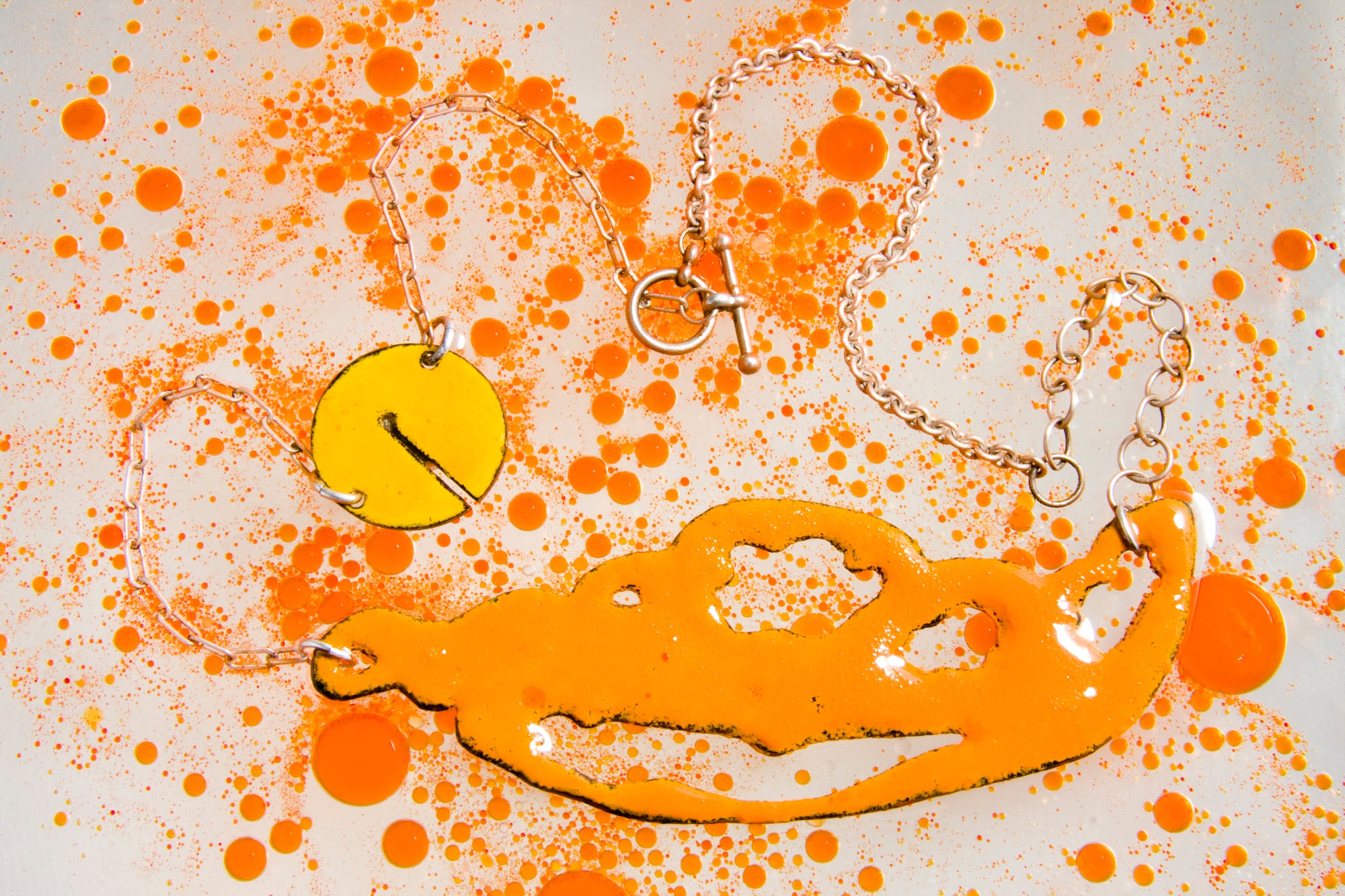 Vitreous enamel bright orange and marigold glass enamel phasmid necklace. phasmid is the sensory organ of some parasites. this necklace is handmade with a granular sugar fired finish by Peggy Skemp 2008. Photo with orange bubbles by AJ Kane 