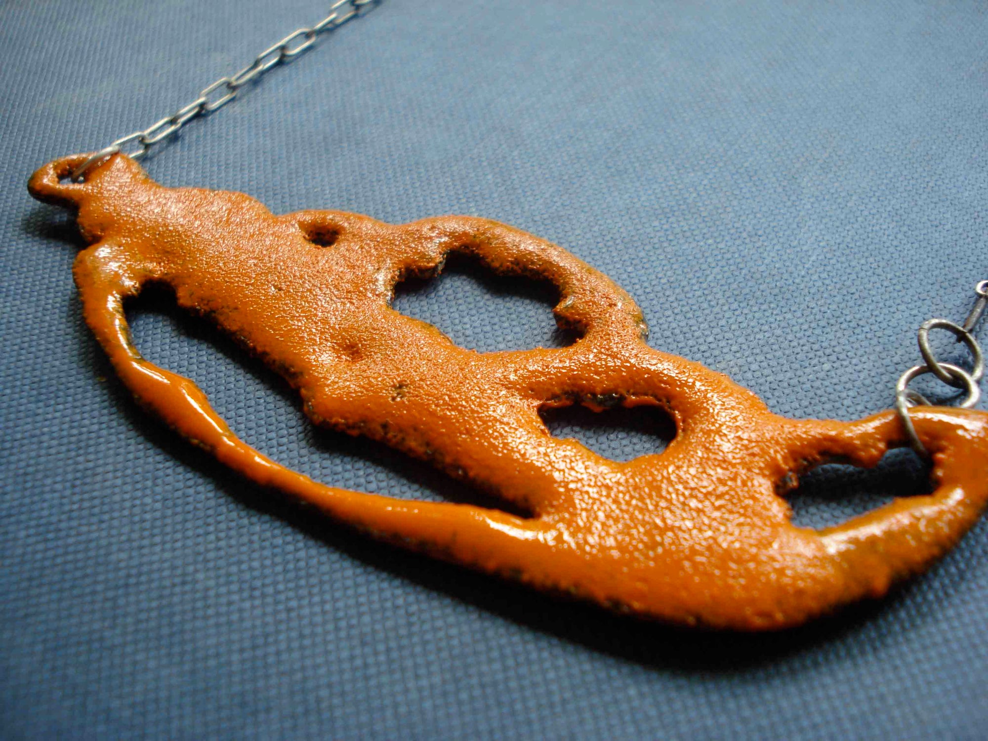 Vitreous enamel bright orange and marigold glass enamel phasmid necklace. phasmid is the sensory organ of some parasites. this necklace is handmade with a granular sugar fired finish by Peggy Skemp 2008. Photo with orange bubbles by AJ Kane 
